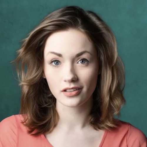 A closeup of Mackenzie Newbury wearing a salmon colored tee shirt and standing in front of a greenish blue background