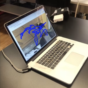 A still image from a demonstration of browser-based motion capture. There is a squiggly blue scribble overtop a webcam feed displayed on a laptop.