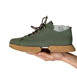 A green pair of sneakers with cork soles over a white background 