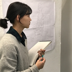 A student examines a piece of art while taking notes.