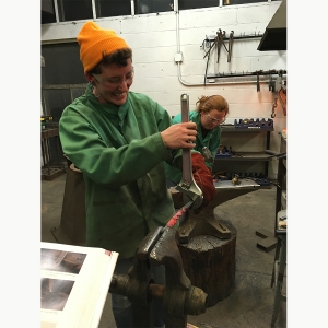 Students use a large wrench to bend fired metal