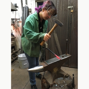 A student hammers fired metal on an anvil