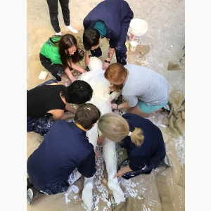 Sculpture students and faculty work on molding a human body