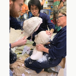 Sculpture students and faculty work together to remove a bust from the mold