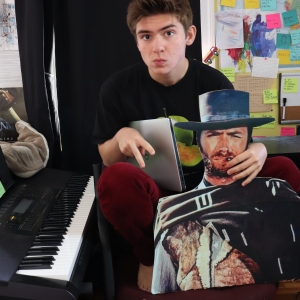 Photo of Daniel next to piano, cardboard cutout, and laptop