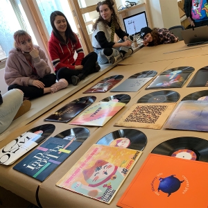 Students sit around a set of album covers that they designed. 