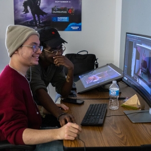 Two students work together using a computer and tablet to create an animation project in the Game Art program.