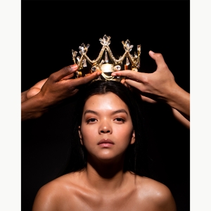 A photo of a two hands placing a gold crown on the head of a woman