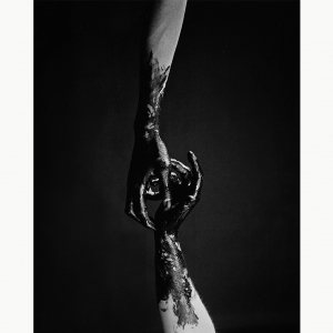 A photography of two hands reaching out to each other covered in black paint