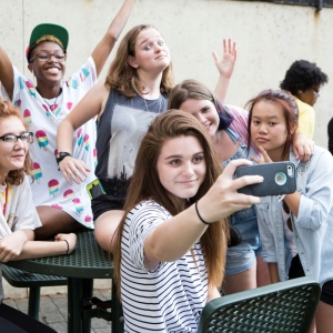 Students sit around an outdoor table and take a selfie
