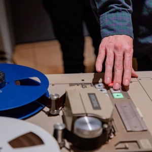 A student presses pause on an analog recorder in the music studio