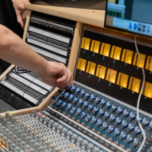 Students mix sound on the mixing board in the recording studios