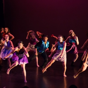 Dancers extend their legs out to the side on stage during a performance