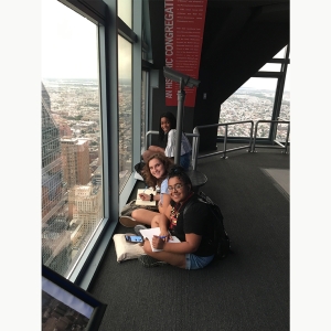 Students sit and write while looking at the Philadelphia skyline