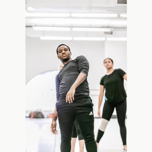 A dancer leans back while practicing choreography in the studio
