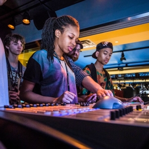 Students mix sound on the mixing board in the studio