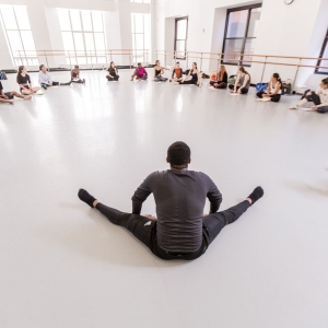 Dancers sit in a circle with notebooks and have a discussion