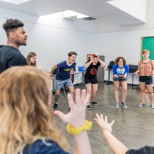 Theater students stand in a circle and emote in the classroom
