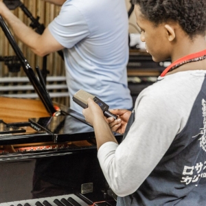 A student places a mic on the piano in the studio