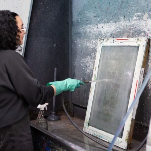A Screenprinting student cleans their screen at the washing station