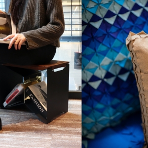 A split image: a person sitting on a shelf-like stool on the left with a book in their lap. Only their legs, feet, arms and torso are visible - the image seems to focus on the stool, which has books resting inside of it. On the right, triangular patterned fabric-like surface designs appear to make up a throw blanket and a pillow. The material seems stiff. The object in the background is in various shades of blue, while the object in the front is cardboard-like in color and texture. 
